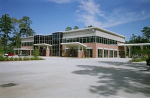 office building with parking lot and trees